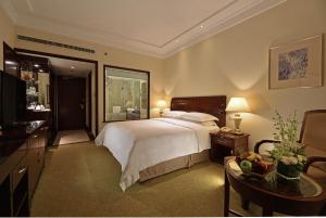 a bedroom with a large bed and a desk and a table sidx sidx at Hotel Equatorial Shanghai in Shanghai
