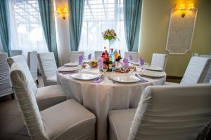 een eetkamer met een tafel met witte stoelen bij Pensiune Perla in Susenii Bîrgăului