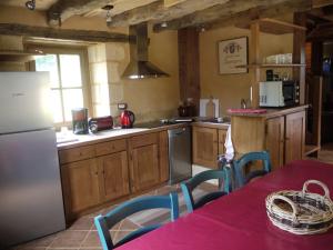 uma cozinha com um frigorífico e uma mesa com cadeiras em Maison Milou em Beynac-et-Cazenac
