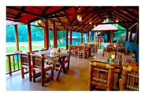 un restaurante con mesas de madera y sillas en una habitación en Vayal Veedu - Luxury Farm Villas by the woods, en Muthanga