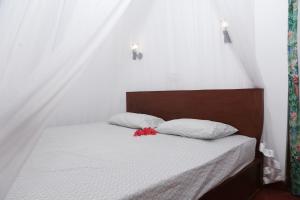 a bed with two pillows and a red flower on it at Vivid Lanka in Bentota
