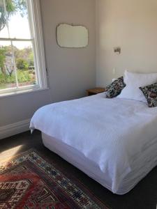 - un lit blanc dans une chambre avec fenêtre dans l'établissement La Rocque Cottage, à Martinborough