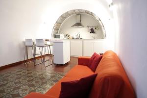sala de estar con sofá naranja y cocina en The House, en Catania