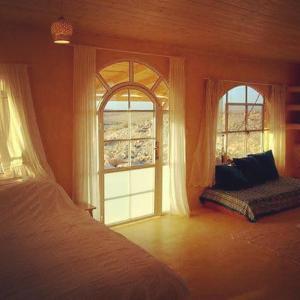 a bedroom with two large windows and a bed at Hamitzpa- Desert Hosting in Ezuz in ‘Ezuz