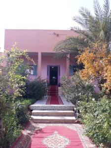ein rosafarbenes Gebäude mit einem roten Teppich davor in der Unterkunft Oasispalmares in Er Rachidia