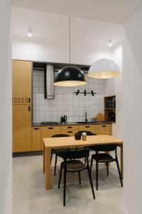 una cucina con tavolo in legno e 2 pendant light di Apartment on Mikhalcuk a Lviv