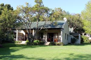 a house with a green lawn in front of it at Blackwaters River Lodge, Knysna in Goukamma