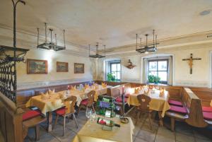 restauracja ze stołami i krzesłami oraz krzyżem na ścianie w obiekcie Hotel Reitlwirt w mieście Brixen im Thale