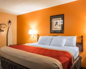 a large bed in a hotel room with orange walls at Econo Lodge Eufaula in Eufaula