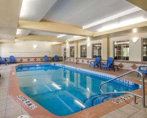 een groot zwembad in een hotelkamer met blauwe stoelen bij Sleep Inn & Suites Springdale West in Springdale