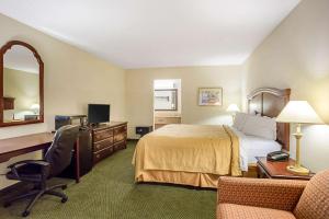a hotel room with a bed and a desk and chair at Quality Inn & Conference Center in Heber Springs