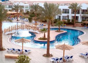 a beach with a pool, chairs, tables and umbrellas at Panorama Naama Heights in Sharm El Sheikh
