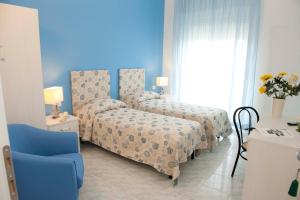 a blue room with two beds and a blue chair at Hotel Venere in Ascea