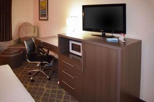 una habitación de hotel con TV en un armario de madera en American Inn & Suites West Memphis, en West Memphis