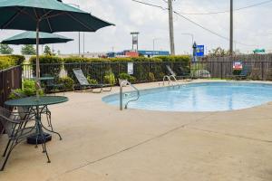 a swimming pool with a table and an umbrella at American Inn & Suites West Memphis in West Memphis