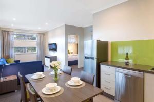 a kitchen and living room with a table with chairs and a refrigerator at Comfort Inn & Suites Warragul in Warragul