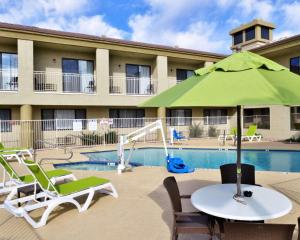 a pool with a table with an umbrella and chairs at Comfort Inn Fountain Hills - Scottsdale in Fountain Hills