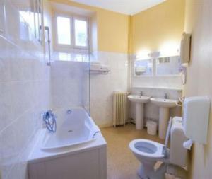 łazienka z umywalką, toaletą i wanną w obiekcie Hôtel Adour w mieście Pau