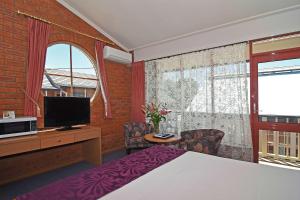 a bedroom with a bed and a tv and a window at Main Lead Ballarat Motel in Ballarat