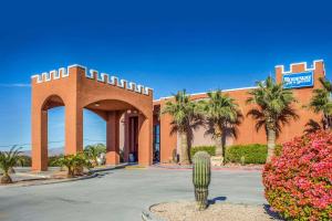 a building with palm trees and a building with a sign at Rodeway Inn & Suites Lake Havasu City in Lake Havasu City