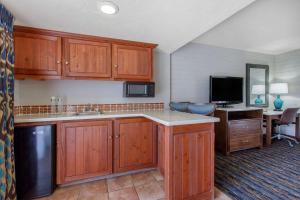 a kitchen with wooden cabinets and a desk and a television at La Posada Lodge & Casitas, Ascend Hotel Collection in Tucson