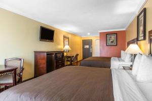 a hotel room with two beds and a flat screen tv at Quality Inn & Suites Bell Gardens-Los Angeles in Bell Gardens
