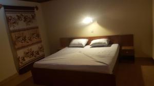 Schlafzimmer mit einem Bett mit weißer Bettwäsche und Kissen in der Unterkunft Yuna Village Garden Resort in Tubaya