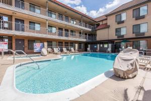 a pool in front of a hotel with tables and chairs at Quality Inn & Suites Bell Gardens-Los Angeles in Bell Gardens