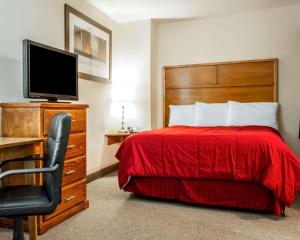 a bedroom with a bed with a red bedspread and a television at Sea Drift Inn in Eureka