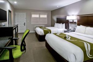 a hotel room with two beds and a desk at Bay Area Inn & Suites in Hayward