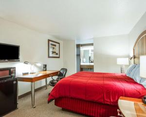 Habitación de hotel con cama roja y escritorio. en Sea Drift Inn, en Eureka