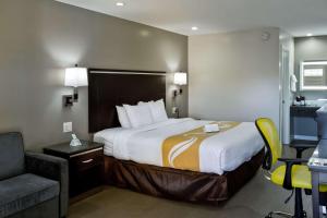 Una habitación de hotel con una cama grande y una silla. en Bay Area Inn & Suites, en Hayward