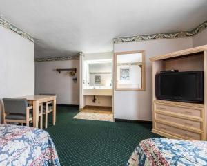 Cette chambre comprend 2 lits, une table et une télévision. dans l'établissement Rodeway Inn Monterey Near Fairgrounds, à Monterey