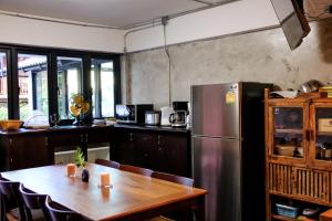 a kitchen with a wooden table and a refrigerator at Baan Lung Poshtel in Chiang Mai