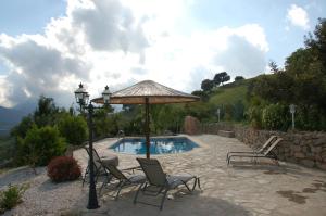 a patio with chairs and an umbrella and a pool at Cortijo Lagarín in El Gastor