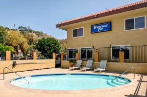 uma piscina em frente a um hotel com cadeiras e um edifício em Rodeway Inn San Diego Mission Valley/SDSU em San Diego