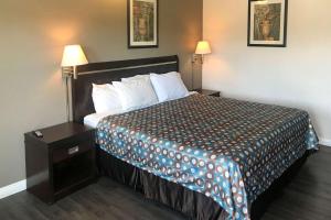 a hotel room with a large bed and a night stand at Rodeway Inn Ontario Mills Mall in Guasti