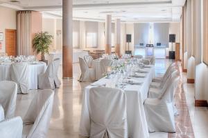 un salón de banquetes con mesas blancas y sillas blancas en Hotel Zalle Don Fernando en Granda
