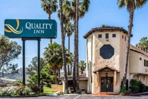 a sign in front of a building with palm trees at Quality Inn Fallbrook in Fallbrook
