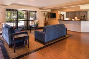 a living room with two blue chairs and a table at Rancho Cordova Inn in Rancho Cordova