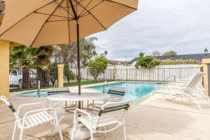 een tafel en stoelen met een parasol naast een zwembad bij Quality Inn & Suites Gilroy in Gilroy