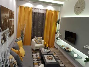 un soggiorno con divano, tavolo e orologio. di 'Golden Aurora' Apartment With Elegant Style ad Atene