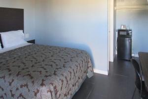 a small bedroom with a bed and a small refrigerator at Rodeway Inn San Pablo in San Pablo