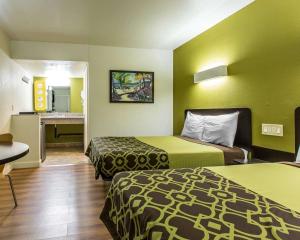 a hotel room with two beds and a desk at Rodeway Inn Downtown Hanford in Hanford