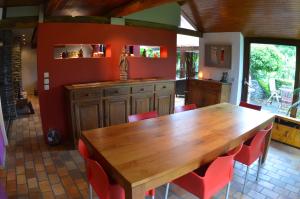 een keuken met een houten tafel en rode stoelen bij Les Bambous in La-Roche-en-Ardenne