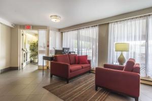 a living room with two red chairs and a piano at Comfort Inn in Sault Ste. Marie