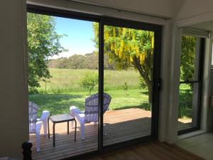 a sliding glass door with a table and chairs on a deck at Langleys Port Campbell Hobby Farm in Port Campbell