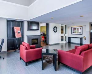 a living room with two red chairs and a fireplace at Comfort Inn East in Sudbury
