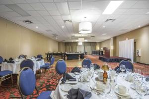ein Konferenzraum mit Tischen und blauen Stühlen und ein Raum mit einer Bühne in der Unterkunft Quality Hotel & Conference Centre in Fort McMurray