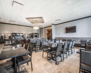 une salle à manger avec des tables et des chaises noires dans l'établissement Quality Suites, à Drummondville